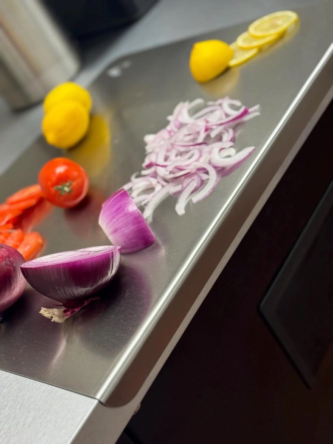 Chopped onions, tomatoes, and lemons on a brushed stainless STELEBOARD